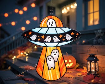 May include: A Halloween-themed hanging decoration shaped like a UFO, featuring ghosts and stars. The decoration has a black and blue saucer with orange and white accents. It is hanging outside with a pumpkin and lantern in the background.