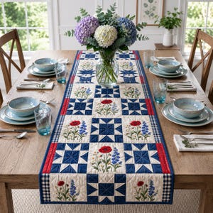 Puede incluir: Una mesa de comedor preparada para una comida, con un centro de mesa floral y un camino de mesa acolchado. El camino de mesa tiene un patrón de estrellas azules y blancas con flores bordadas, bordeado por rojo y un estampado de cuadros blancos y negros. La mesa está puesta con cuencos y vasos azules.