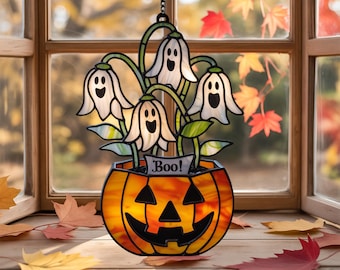 May include: A stained glass Halloween decoration featuring a jack-o'-lantern pot with ghost-like flowers. The flowers are white with black facial features and green stems. The pot has an orange and yellow glow, and the word "Boo!" is on a banner.