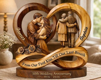 May include: Wooden sculpture commemorating a 50th wedding anniversary. The design features two intertwined heart shapes, one with a couple kissing and the other with an elderly couple. The base reads "From Our First Kiss Till Our Last Breath."