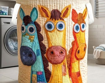 May include: A beige, quilted laundry hamper featuring three whimsical horse faces in shades of blue, yellow, and orange. The horses have large, expressive eyes and are appliquéd onto the hamper. White handles are attached to the top.