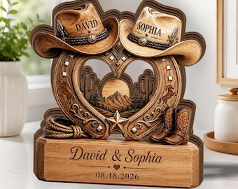 May include: A wooden decorative display featuring two cowboy hats labeled David and Sophia, a heart-shaped frame with a desert landscape, a coiled rope, and a pair of boots. The base is engraved with David & Sophia and the date 08.18.2026.