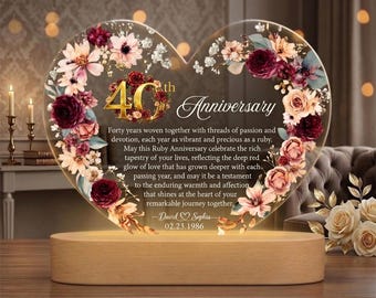 May include: A heart-shaped anniversary gift with floral accents and the text "40th Anniversary." The clear acrylic piece sits on a wooden base, illuminated from below. The text includes a personalized message and date.