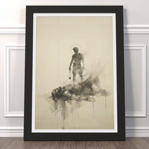 May include: Framed artwork with a sepia-toned illustration. A figure with a halo stands over a figure lying down, both in grey tones. The artwork is in a black frame with a white mount.