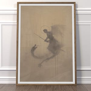 May include: Framed art print showing an angel with a sword fighting a dragon. The artwork uses grey and brown tones, with a halo above the angel's head. The print is presented in a wooden frame.