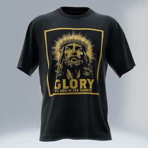 Puede incluir: Camiseta negra con una ilustración dorada de Jesús con una corona de espinas y un halo radiante. El texto "GLORY TO GOD IN THE HIGHEST" está en dorado debajo de la imagen. La camiseta tiene mangas cortas.