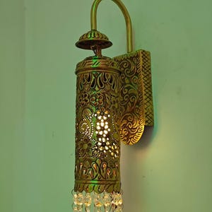 Vintage brass wall light fixture with hand pierced floral design and warm glow
