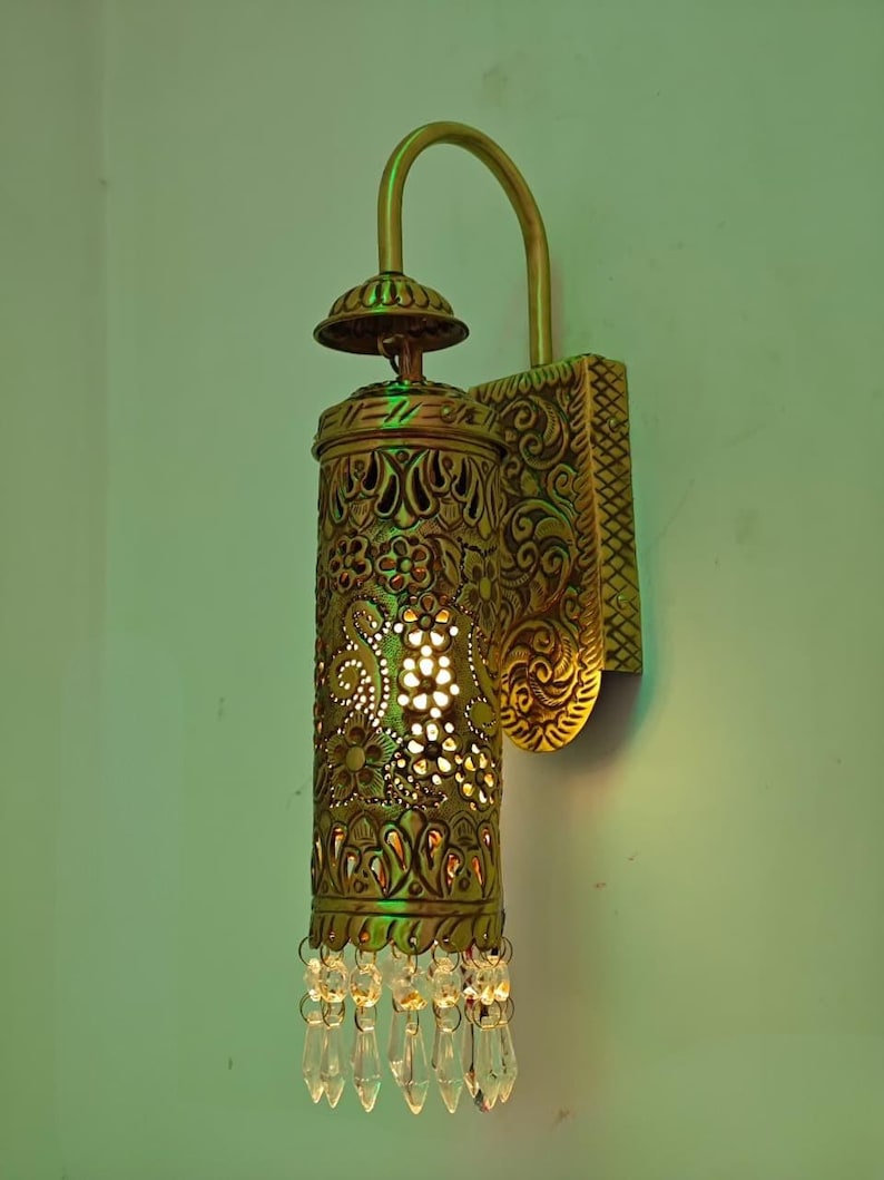 Vintage brass wall light fixture with hand pierced floral design and warm glow