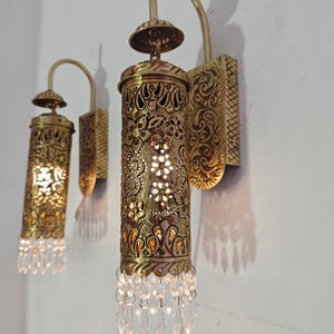 Ornate brass wall sconce with pierced metal shade and crystals