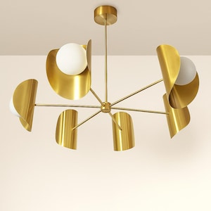 May include: A modern brass chandelier with a central hub and radiating arms. Each arm supports a white globe light and a curved brass shade. The fixture is designed for ceiling mounting and adds a touch of elegance.