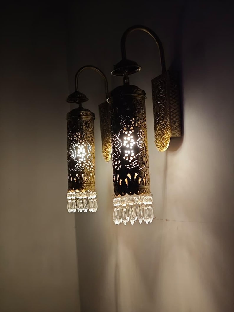 Antique brass wall lamp with pierced metal shade casting decorative shadows