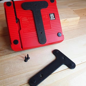 May include: A red and black power adapter with a T-shaped stand. The adapter has a label that reads "ozito PXCG-030 18V Li-Ion Battery Charger".