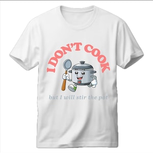 Puede incluir: Camiseta blanca con un gráfico rosa de una olla arrocera de dibujos animados sosteniendo una cuchara de madera. El texto "No cocino pero sí removeré la olla" está impreso en rosa debajo de la imagen.