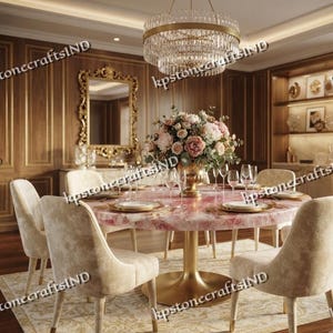 May include: A round dining table with a polished pink stone top and a gold pedestal base, surrounded by four beige upholstered chairs. A large floral centerpiece sits in the center, beneath a tiered crystal chandelier with gold accents.