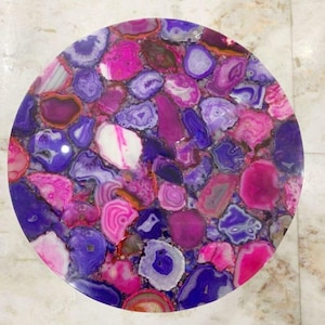 May include: A round table top composed of polished agate slices in shades of pink, purple, and white. The agate pieces are arranged in a mosaic pattern, creating a vibrant and unique surface. The table top is approximately 30 inches in diameter.