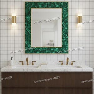 May include: A rectangular mirror with a malachite green frame and gold trim hangs above a double sink vanity. The vanity has a dark brown cabinet with two drawers, white marble countertop, and gold faucets. Two gold sconces flank the mirror.