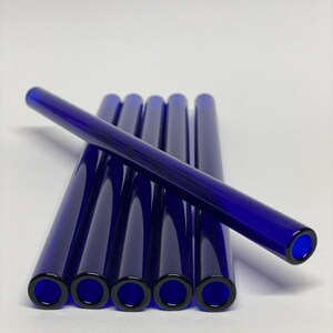 Può includere: Set di sei cannucce per bere in vetro blu. Le cannucce sono disposte a ventaglio, con una cannuccia che si estende sulle altre.