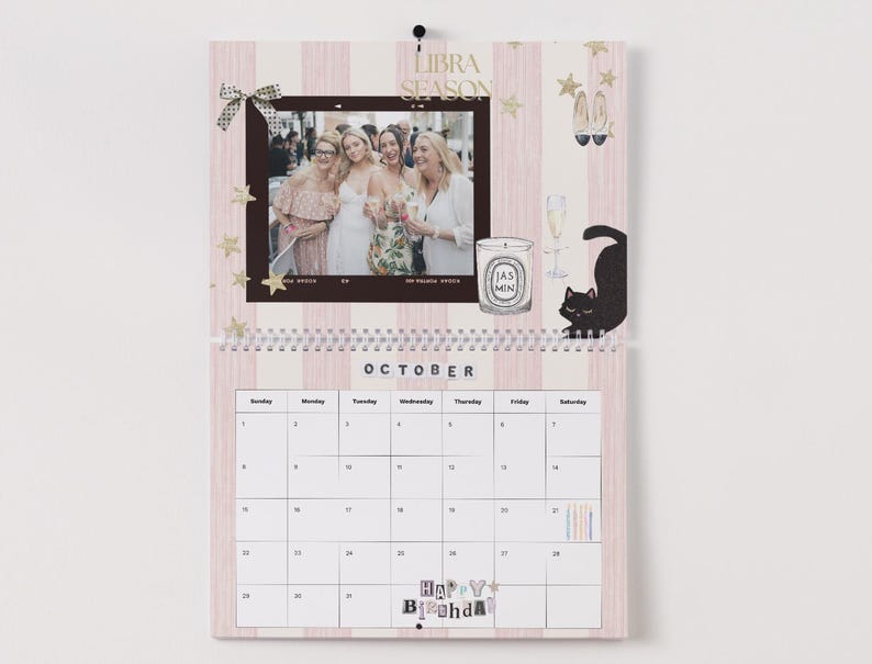 May include: A pink and white striped wall calendar for October, featuring a photo, candle, and cat illustration. The calendar includes the text "Libra Season" and "Happy B'day". The calendar is spiral-bound.