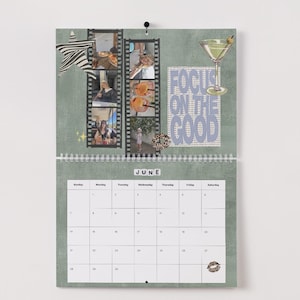 May include: A wall calendar for June with a green background, featuring filmstrip-style photo collages, a martini glass illustration, and the text "FOCUS ON THE GOOD." The calendar has a spiral binding and a white date grid.
