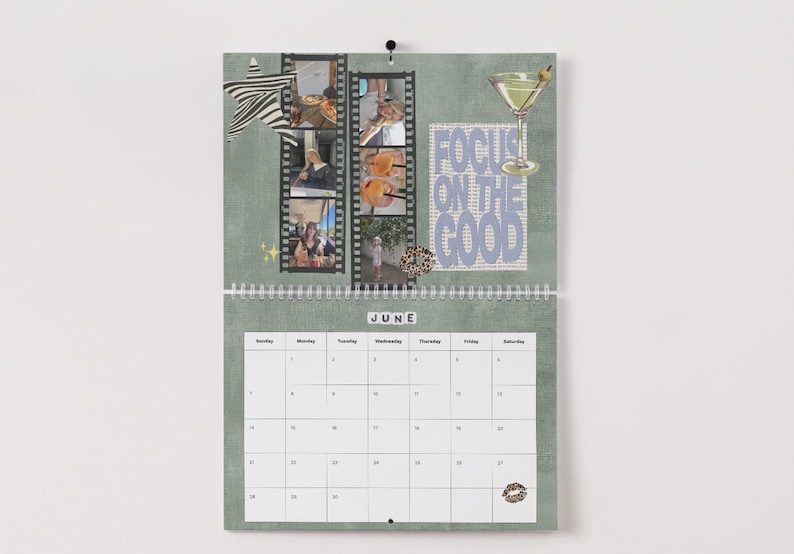 May include: A wall calendar for June with a green background, featuring filmstrip-style photo collages, a martini glass illustration, and the text "FOCUS ON THE GOOD." The calendar has a spiral binding and a white date grid.