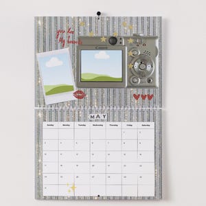 May include: A decorative calendar with a silver glitter background, featuring a digital camera, a polaroid-style photo, and the text "You are My Favorite." The calendar displays the month of May.