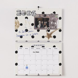 May include: A spiral-bound calendar for the year 2026, featuring a January page with a polka dot design. The calendar includes a photo, a gold star, and the handwritten phrase "a lot can happen in a year."
