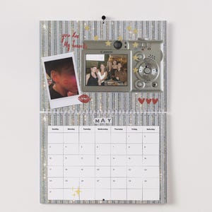 May include: A decorative calendar with a silver and white striped background. It features a photo of a person, a digital camera, and a photo of a group of people. The calendar displays the month of May and has a grid of dates.