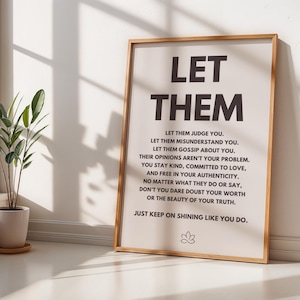 Puede incluir: Un cartel enmarcado con las palabras "LET THEM" en letras grandes y en negrita en la parte superior. Debajo, el texto continúa con citas inspiradoras. El marco es de color marrón claro. Una planta en maceta se encuentra cerca de una ventana en el fondo.