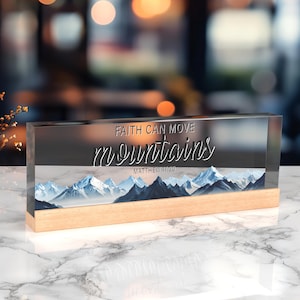Könnte beinhalten: Ein klarer Glasblock mit Holzsockel zeigt ein Bild einer Bergkette und den Text "FAITH CAN MOVE MOUNTAINS" mit dem Bibelvers "MATTHEW 17:20".