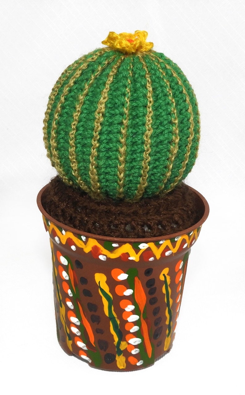 May include: A handcrafted, green crocheted cactus with gold stripes and a yellow flower, potted in a brown, hand-painted pot with colorful designs. The cactus is a unique decorative item.
