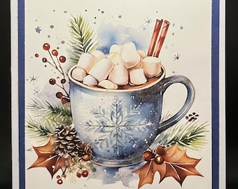 May include: A greeting card with a watercolor illustration of a mug filled with marshmallows and cinnamon sticks. The mug is blue with a snowflake design. The card has a blue border and winter-themed decorations.