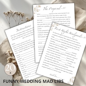 Könnte beinhalten: Ein druckbares Hochzeitsspiel mit Mad Libs auf hellbraunem Hintergrund mit goldenen floralen Akzenten. Das Spiel umfasst zwei Seiten, eine mit dem Titel "Der Antrag" und die andere mit dem Titel "Erste Nacht der Frischvermählten".