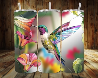 May include: A set of three stainless steel tumblers with a stained glass design featuring a hummingbird and flowers. The hummingbird is green, purple, and blue, and the flowers are pink, orange, and yellow.