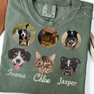 May include: A moss green Comfort Colors t-shirt featuring embroidered pet portraits of a dog, a cat, and a bulldog, with their names below. The shirt also has three circular photos of the pets. The text "Color - Moss" is at the bottom.