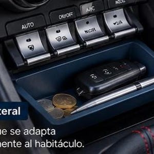 May include: A dark blue plastic storage tray installed in a vehicle center console, containing a black car key fob, a silver metal pen, and several gold-colored coins. The tray is positioned below a row of silver climate control buttons.