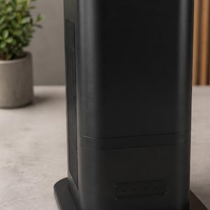 Puede incluir: Un purificador de aire negro, alto y rectangular, con acabado de metal cepillado. El dispositivo cuenta con una rejilla de ventilación vertical en el lateral y un panel de control horizontal con cuatro pequeñas luces indicadoras circulares al frente.