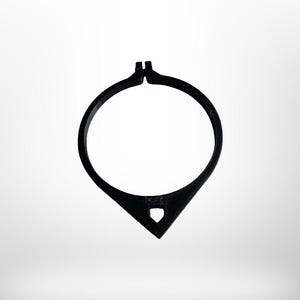 May include: A black, open-circle necklace with a teardrop-shaped pendant. The pendant has a small, diamond-shaped cutout. The necklace is made of a solid, matte material and is set against a white background.