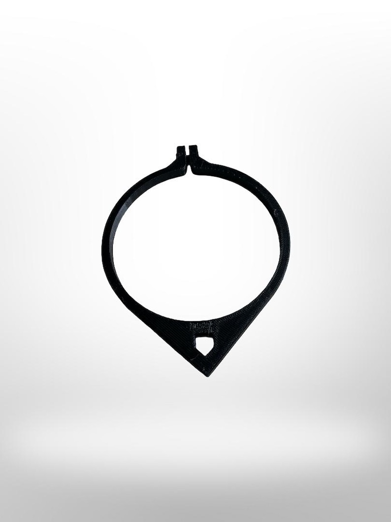 May include: A black, open-circle necklace with a teardrop-shaped pendant. The pendant has a small, diamond-shaped cutout. The necklace is made of a solid, matte material and is set against a white background.