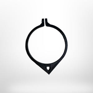 May include: A black, circular object with a teardrop-shaped bottom and a small, shield-like cutout. The top of the circle is split. The object is set against a white background.