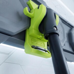 Può includere: Un supporto magnetico per viti verde lime fissato a un pannello a parete modulare grigio. Il supporto presenta un gancio e una fessura contenente un inserto per cacciavite in metallo. Il testo "MAGNETIC SCREW HOLDER" è impresso sul supporto.