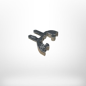 Puede incluir: Una herramienta metálica plateada, con forma de llave estilizada. La herramienta tiene un diseño único de extremo abierto con una superficie texturizada. El objeto se encuentra sobre un fondo blanco liso.