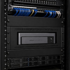 May include: A UGREEN NASync DXP480T Plus device mounted in a black server rack. The unit features a dark gray front panel with a power button and the UGREEN logo. It is positioned between blank rack panels, with network cables visible above.