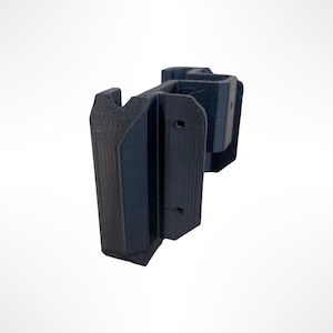 Może przedstawiać: Czarny obiekt drukowany w 3D o geometrycznym kształcie. Obiekt ma prostokątną podstawę z szeregiem pionowych podpór i górną sekcją z zakrzywioną krawędzią. Obiekt ma kilka otworów i prawdopodobnie jest wspornikiem montażowym.