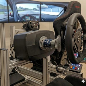 Puede incluir: Una configuración de simulador de carreras negra con volante, asiento y múltiples pantallas que muestran una pista de carreras. El volante tiene un agarre negro y varios botones. La configuración está montada en un marco de metal plateado.