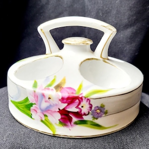 Puede incluir: Soporte para salero y pimentero de porcelana blanca con diseño floral. El soporte tiene un asa y dos compartimentos separados para la sal y la pimienta.