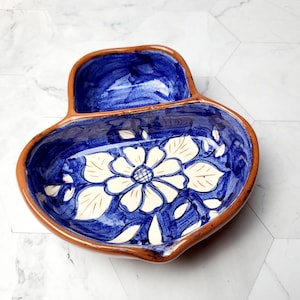 Peut inclure: Plat à servir en céramique peint à la main, intérieur bleu et bord marron. Le plat présente un motif floral blanc au centre. Le plat a deux compartiments, idéal pour les collations ou les trempettes.