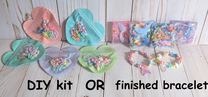 May include: DIY bracelet kits and finished bracelets are displayed. The kits are in heart-shaped bags with beads and elastic. Finished bracelets with mermaid tail charms are also shown. Text reads "DIY kit OR finished bracelet."