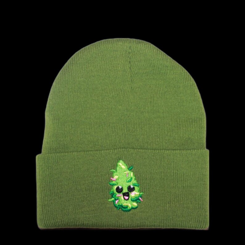 May include: A green beanie with a cute cartoon marijuana leaf embroidered on the front. The leaf has a smiling face and pink cheeks.