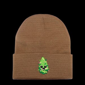 May include: A brown beanie with a green and white embroidered cartoon marijuana leaf with a smiling face.