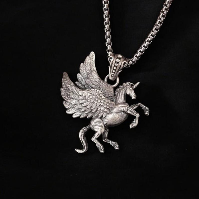 May include: Silver pendant necklace featuring a detailed winged unicorn design. The pendant is attached to a silver chain.
